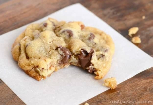 warm cookie on waxed paper with melted chocolate chips oozing out the middle