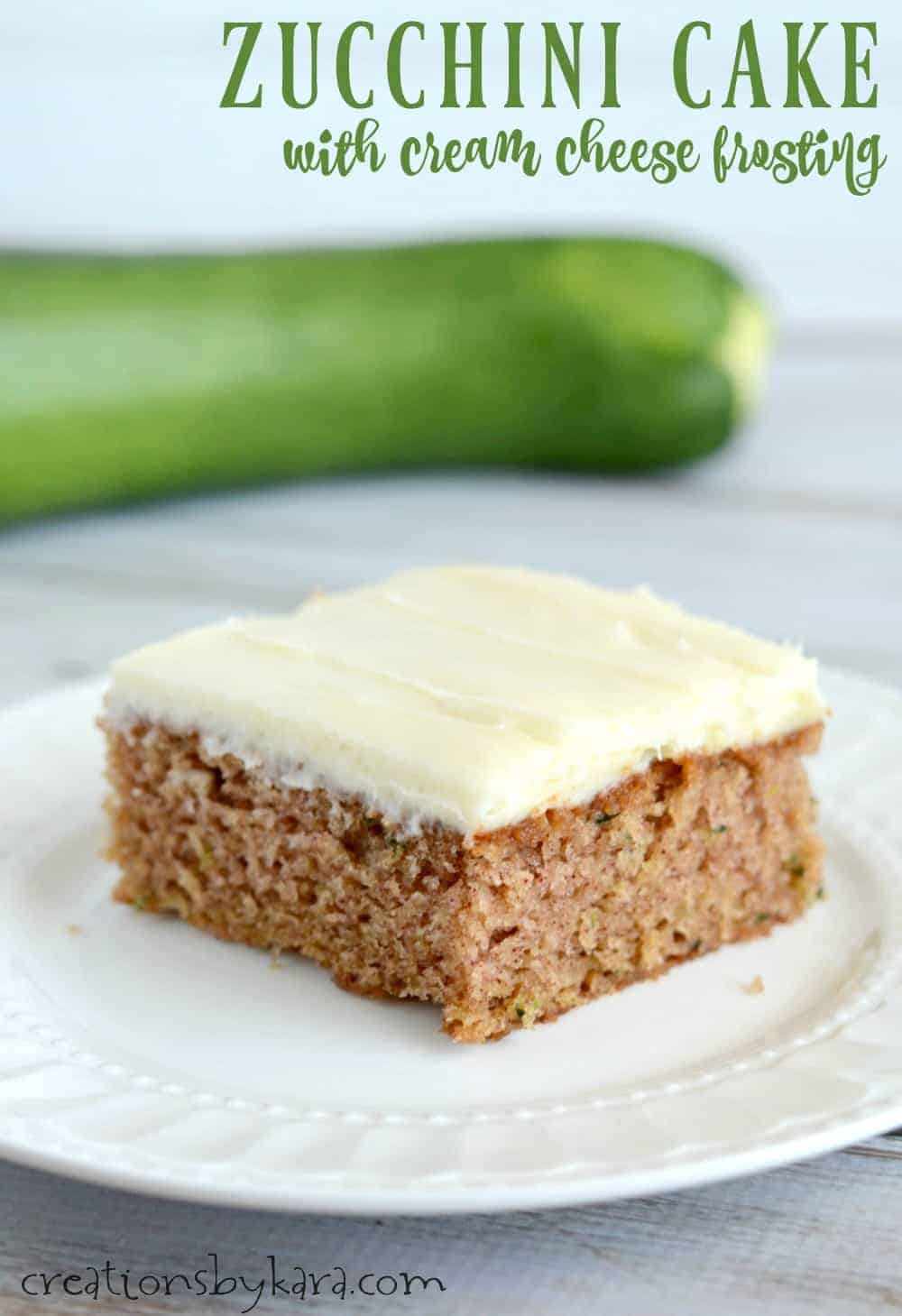 slice of Cinnamon Zucchini Spice Cake with Cream Cheese Frosting on a plate with zucchini in the background