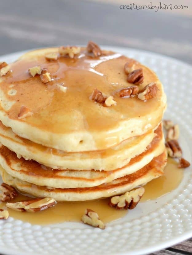 stack of banana pancakes topped with syrup and chopped pecans