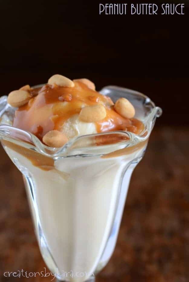 parfait glass with vanilla ice cream topped with peanut butter sauce and peanuts