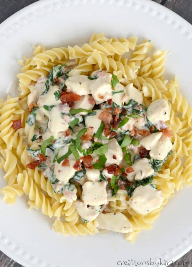 plate of pasta with chicken, sauce, bacon, and spinach