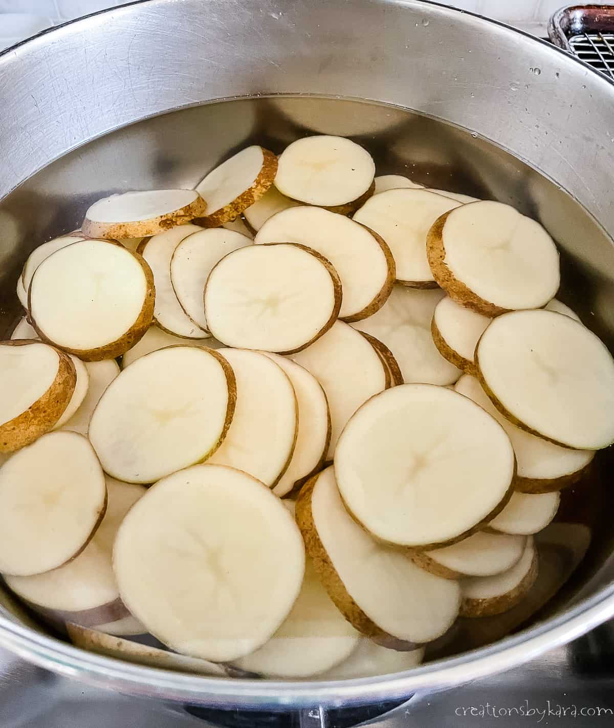 pan of sliced potatoes being parboiled