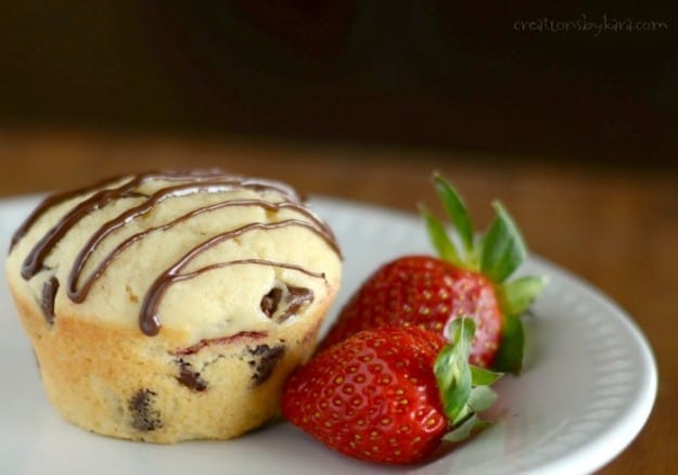Strawberry chocolate chip muffin on a plate with fresh strawberries