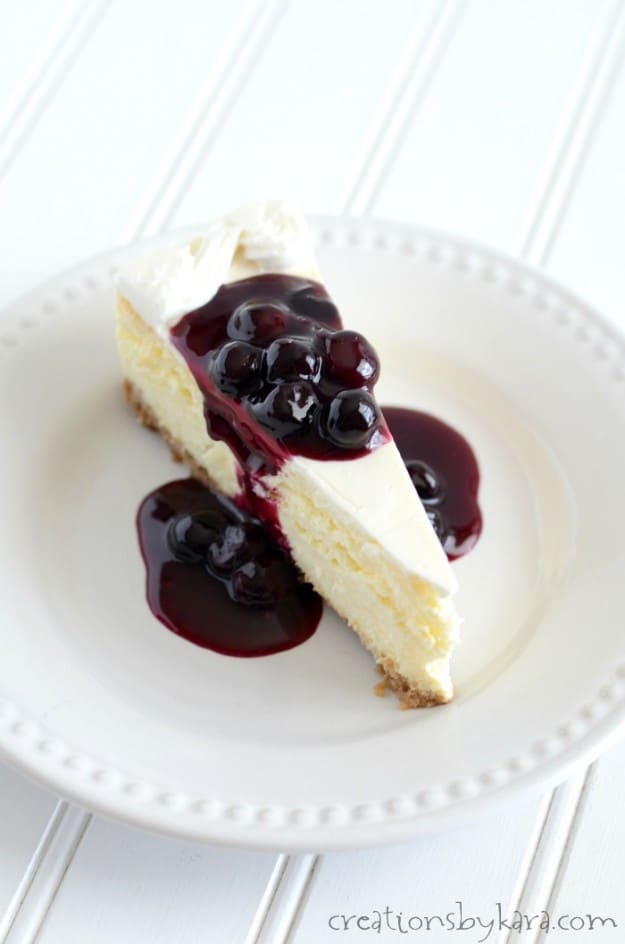 slice of cheesecake on a plate, topped with blueberry sauce