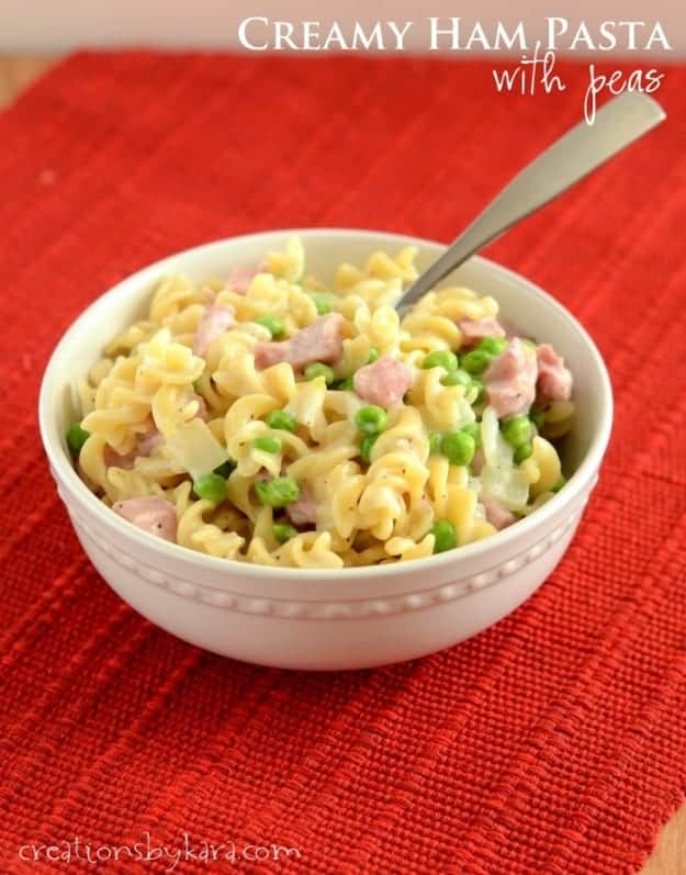bowl of creamy ham and pea pasta on a red tablecloth