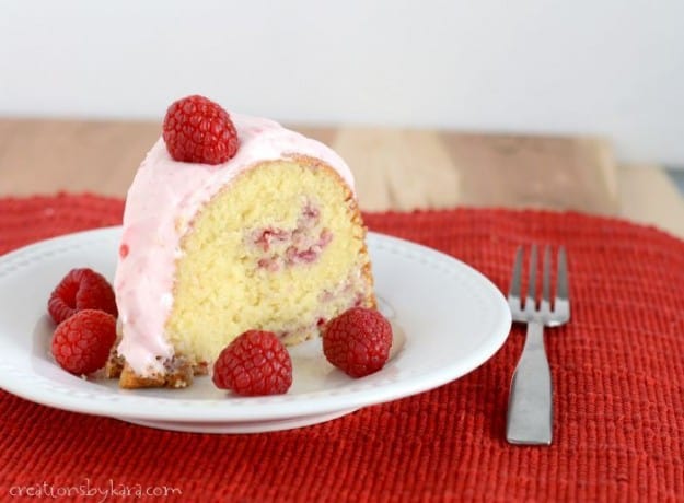 slice of raspberry bundt cake on a plate with fresh raspberries