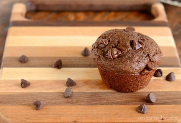 chocolate chocolate chip muffin on a cutting board with chocolate chips