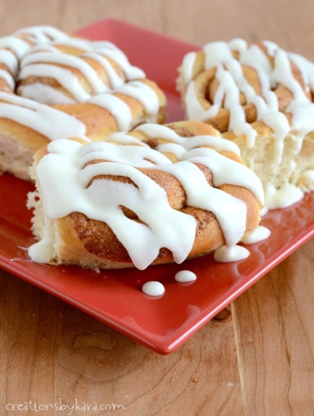 cinnamon rolls on a red plate drizzled with icing