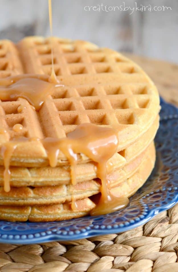 syrup being poured on a stack of waffles on a blue plate