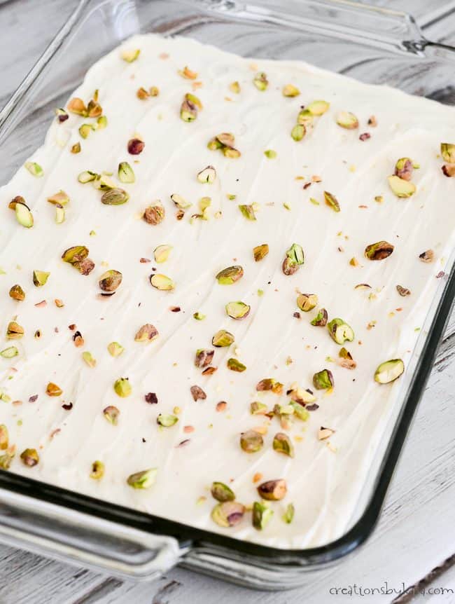 pan of pistachio sugar cookie bars with cream cheese frosting and chopped pistachios