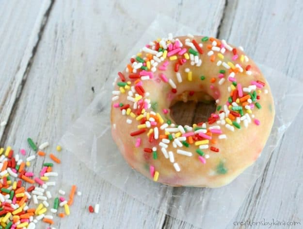 close up of funfetti sprinkled donut with a pile of sprinkles