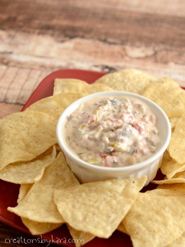 bowl of hot sausage dip with a plate of tortilla chips