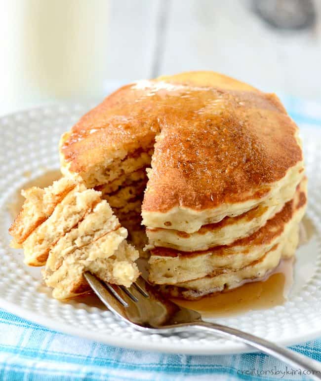 stack of oatmeal pancakes and syrup on a plate with a fork