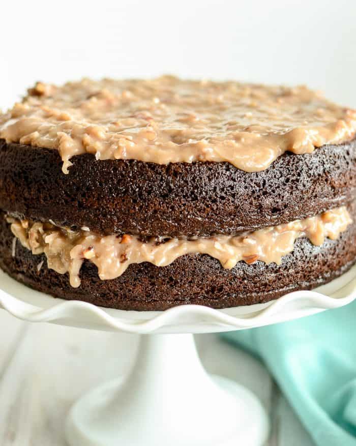 chocolate cake with coconut pecan frosting on a white cake stand