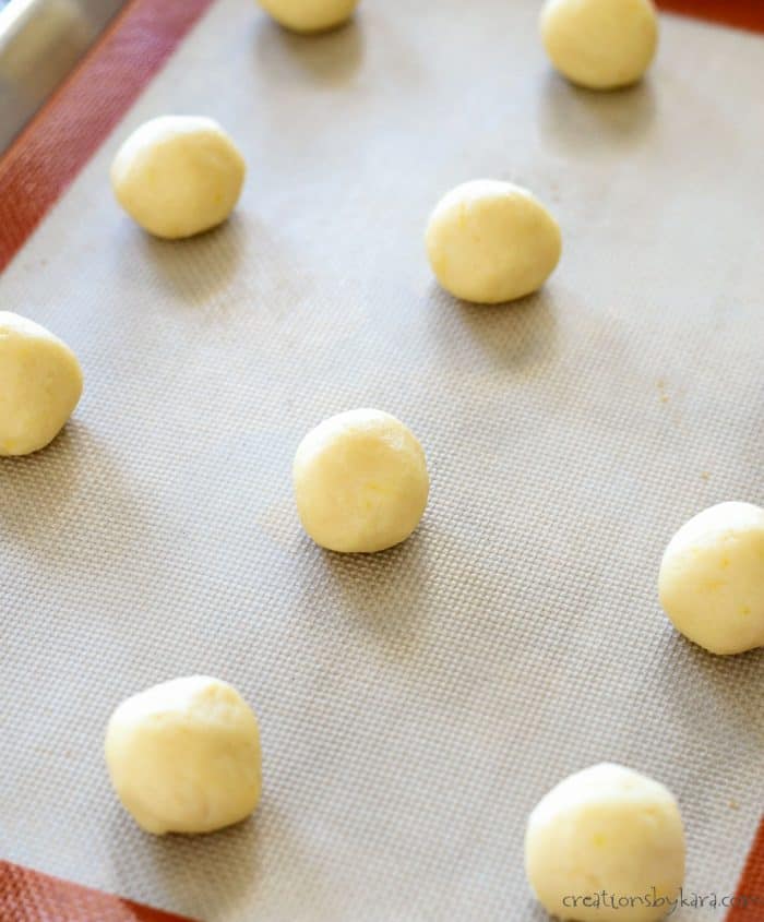 lemon sugar cookie dough balls on a silpat lined cookie sheet