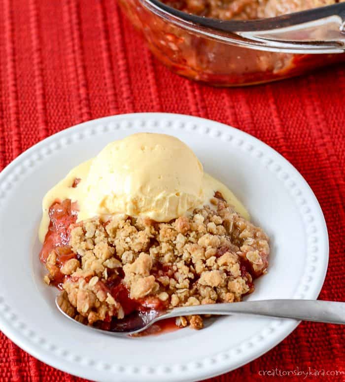 plate of strawberry rhubarb crisp with a scoop of vanilla ice cream