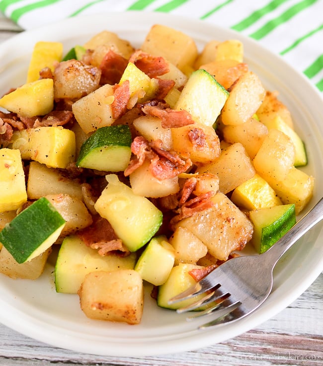 sauteed zucchini, potatoes, and bacon on a plate with a fork