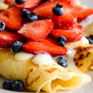 rolled thin pancakes with vanilla sauce and berries