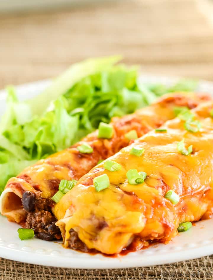ground beef enchiladas on a plate with shredded lettuce