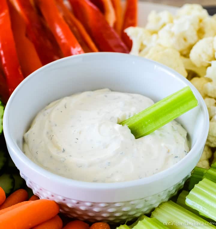 close up of bowl of ranch dip with a piece of celery in it