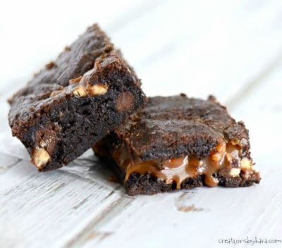 two warm caramel turtle brownies with caramel oozing out