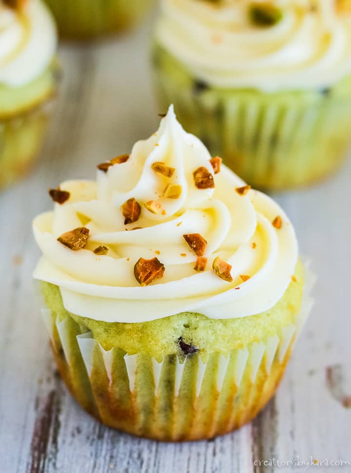 pistachio cupcake topped with cream cheese frosting and chopped pistachios