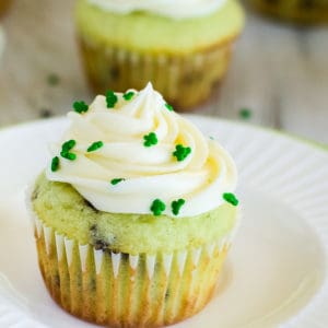 close up of pistachio pudding cupcake topped with frosting and shamrock sprinkles