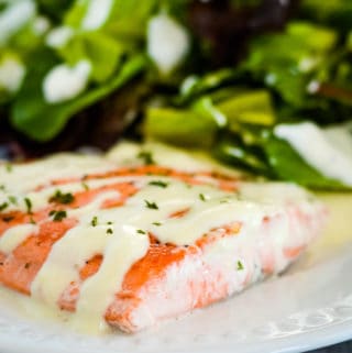 pan seared salmon on a plate drizzled with creamy sauce