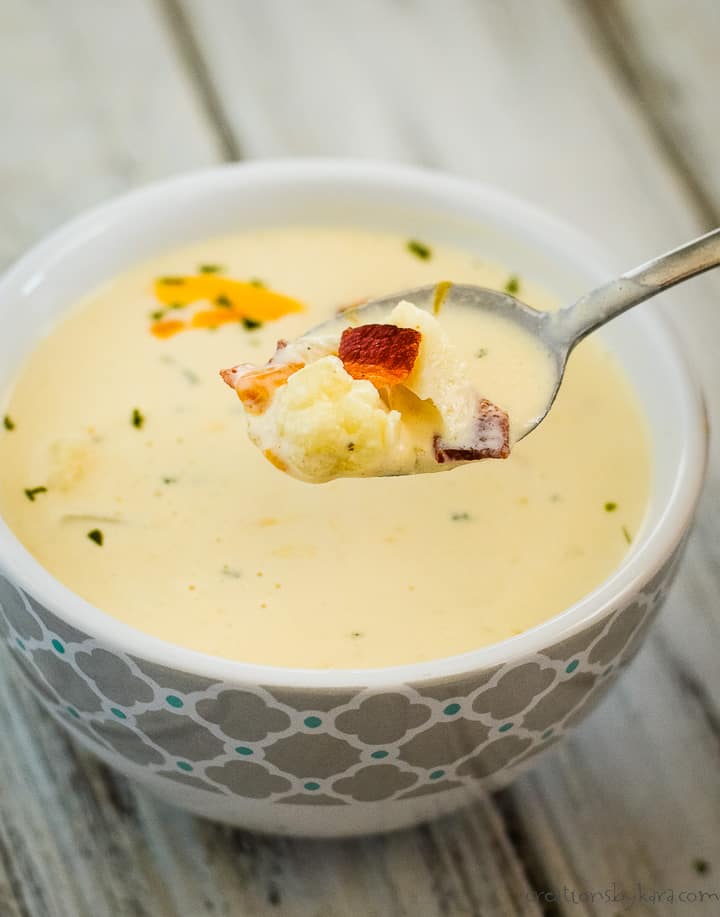 spoonful of cheesy cauliflower soup over a bowl of soup