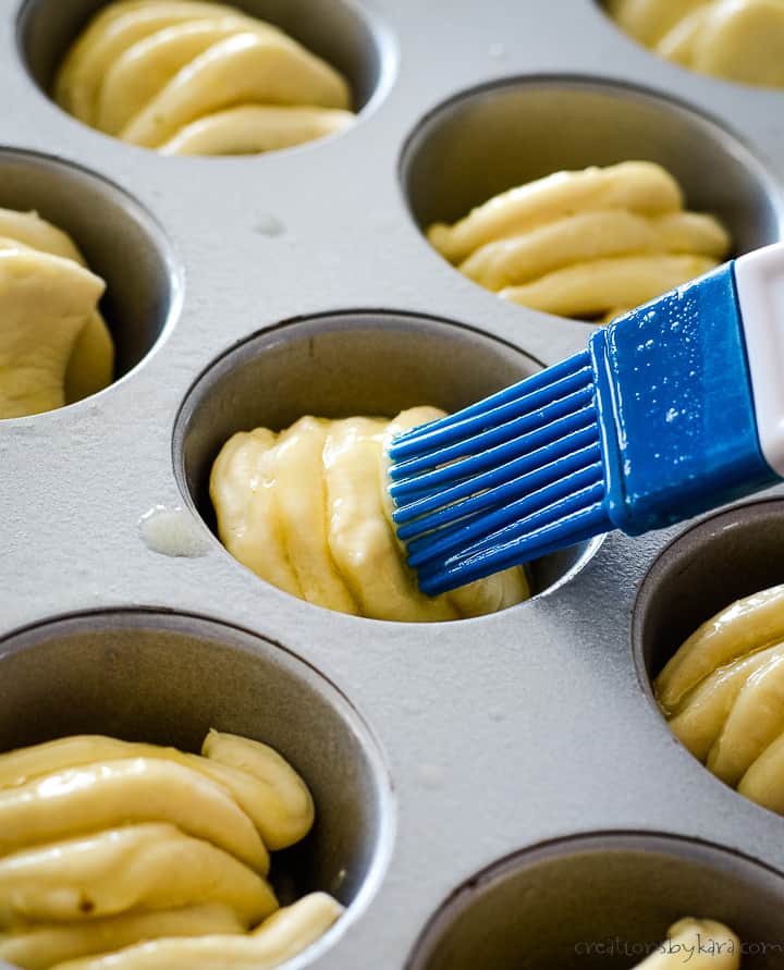 brushing garlic butter on garlic roll dough before baking