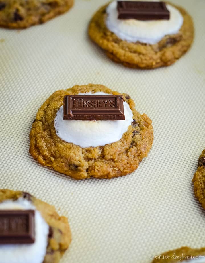 hershey bar on top of marshmallows on smore cookies