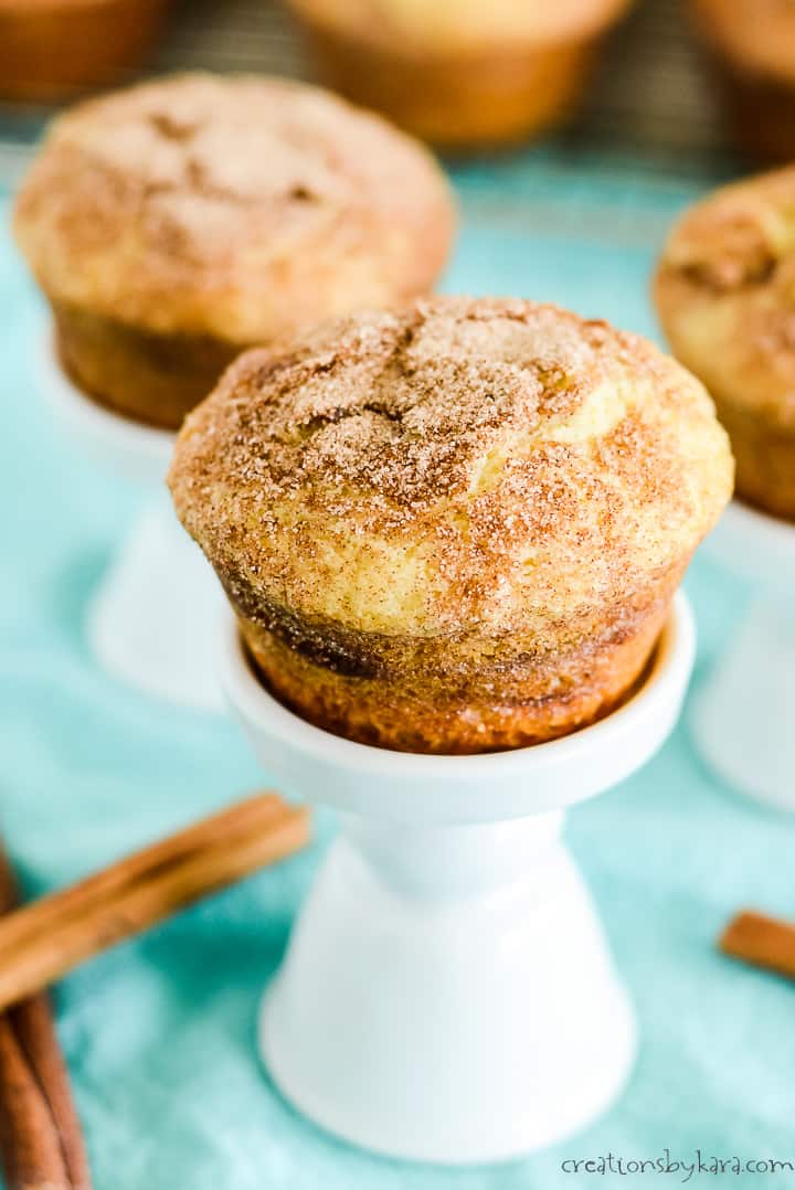 cinnamon swirl muffins on cupcake stands with a blue dish towel and cinnamon sticks