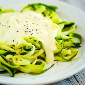 gluten free alfredo sauce over a plate of zoodles