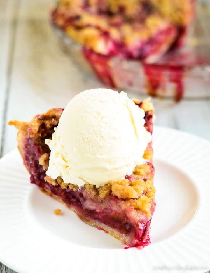 plum pie with crumb topping on a plate with a whole pie in the background