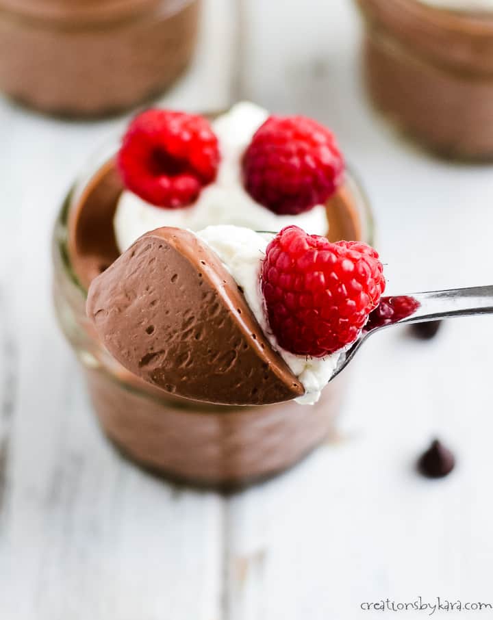 spoonful of dark chocolate mousse with whipped cream and a raspberry