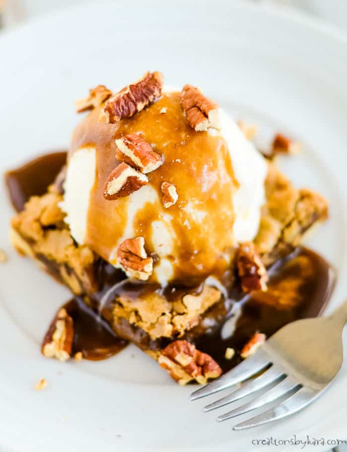 maple brown butter blondies on a white plate with ice cream and maple cream sauce