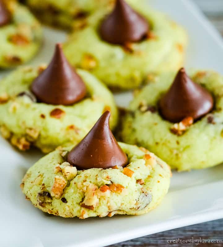 Pistachio Kiss Cookies have pudding mix in the dough, so they are extra soft and yummy! A perfect Christmas cookie recipe. #christmascookies #kisscookies #puddingcookies #pistachiocookies -creationsbykara.com pistachio pudding cookies with a hershey kiss on top
