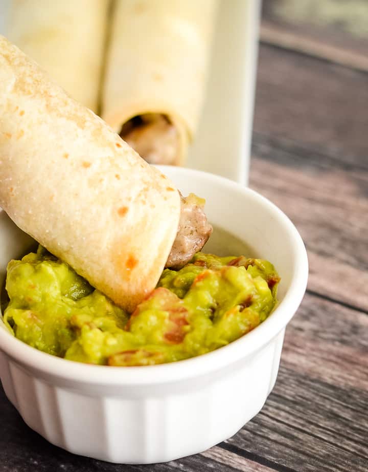 beef taquito being dipped in guacamole