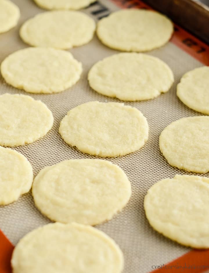 baked sugar cookies with almond extract on a silicone lined cookie sheet