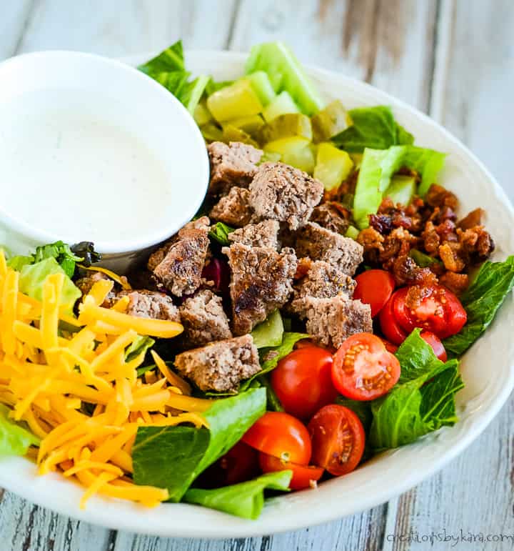 keto big mac salad on a plate with a bowl of dressing