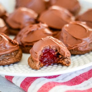 chocolate covered cherry cookies on a plate, one with a bite taken out of it