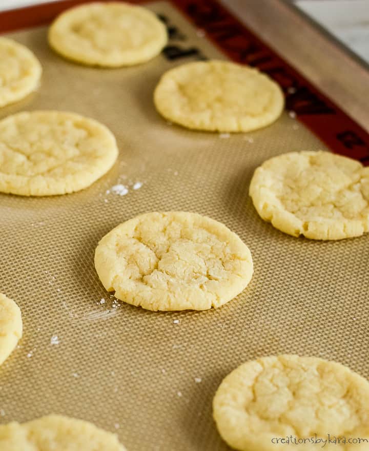 powdered lemon cookies on a cookie sheet lined with silicone