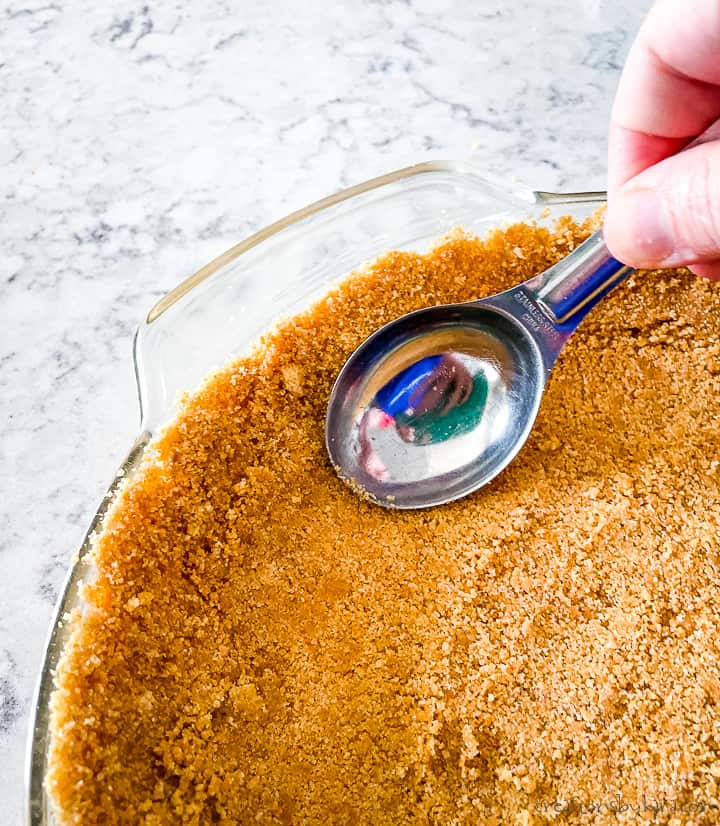 process shot - pressing graham cracker crumbs into pie pan