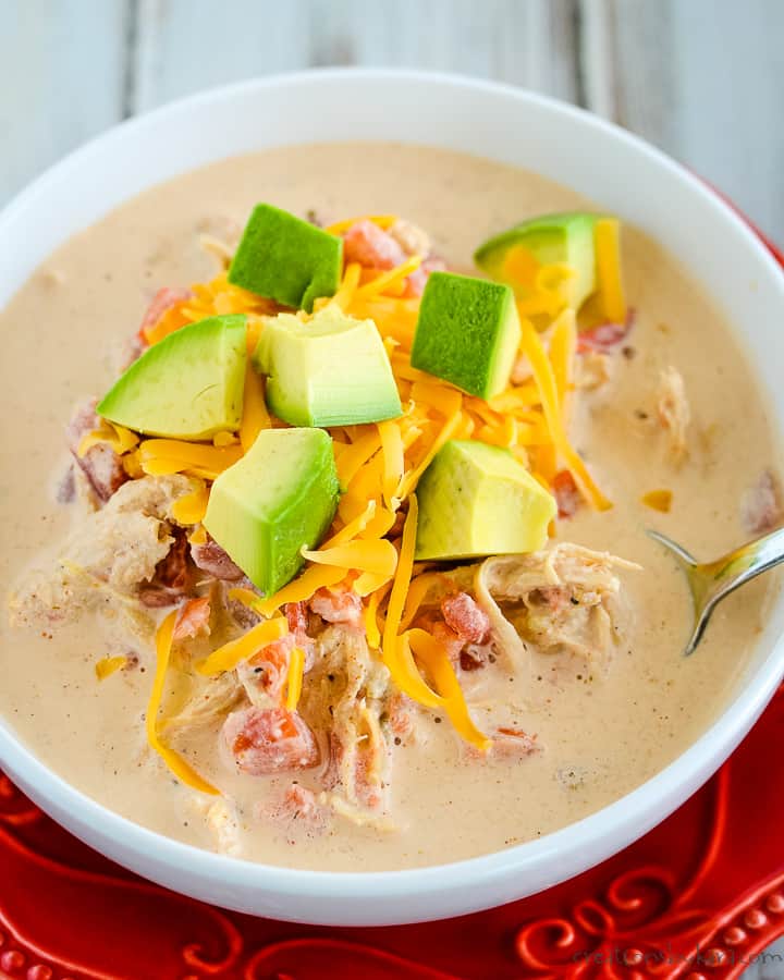 overhead shot of bowl of keto chicken enchilada soup with shredded cheddar and diced avocado