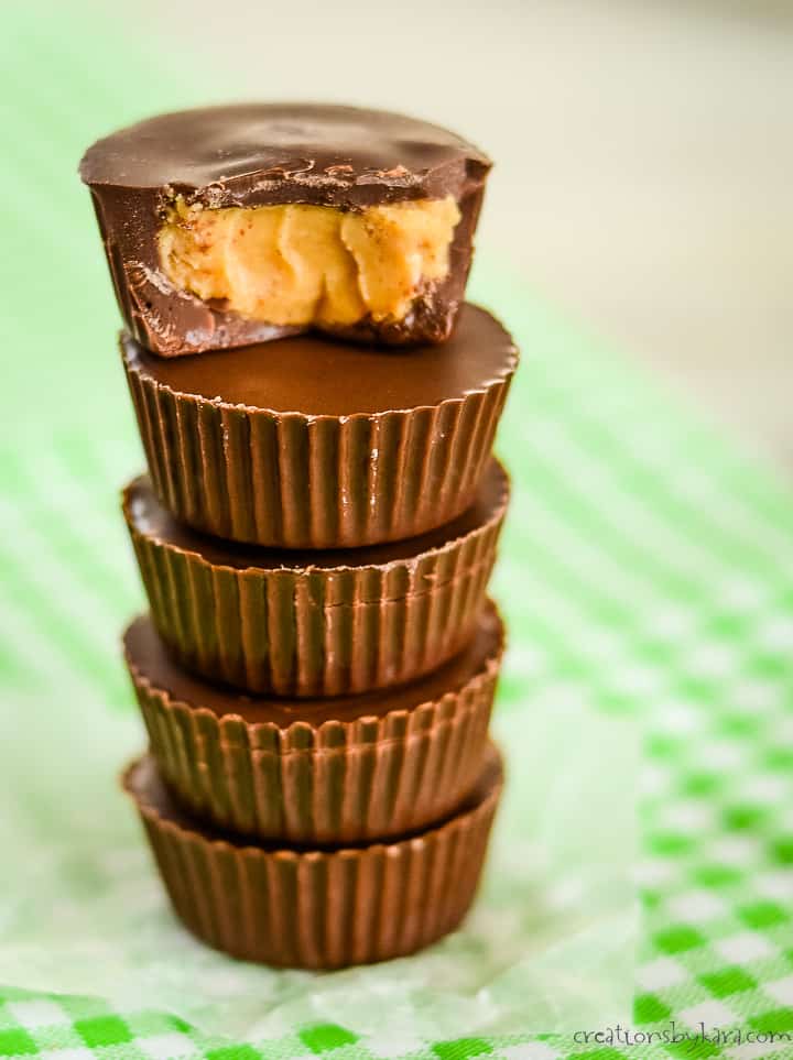 stack of 5 mini keto pb cups on waxed paper, the top one bitten in half