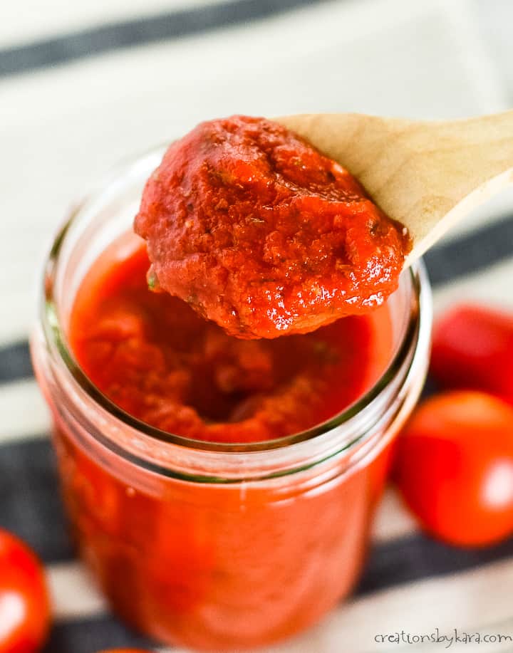 jar of homemade pizza sauce being scooped from a mason jar