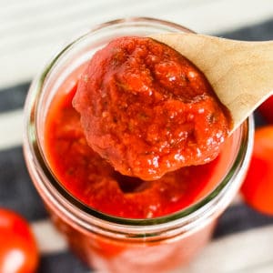 spoonful of homemade pizza sauce being scooped out of a mason jar