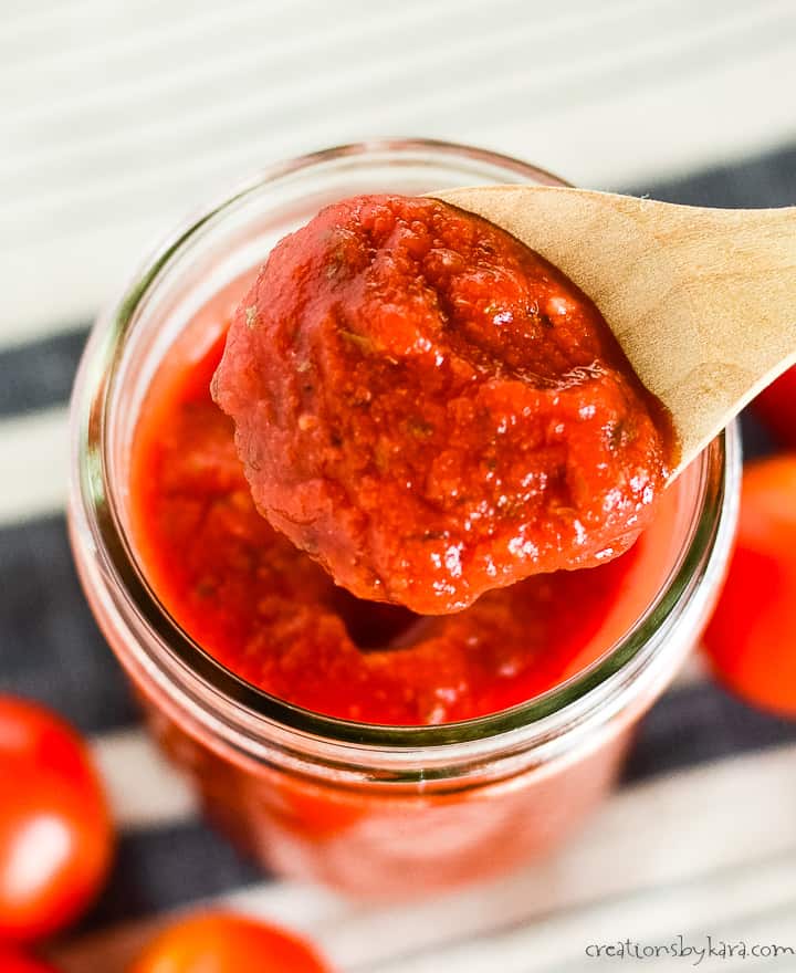 spoonful of homemade pizza sauce being scooped out of a mason jar