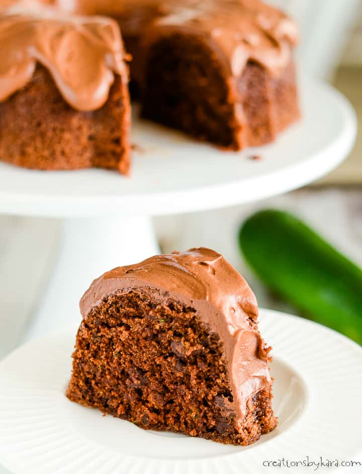 slice of chocolate zucchini cake on a plate with a cake in the background