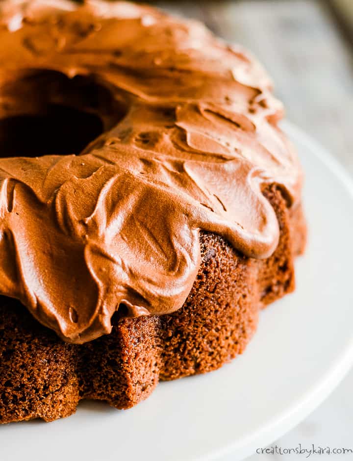 zucchini chocolate cake with chocolate frosting on a white cake stand